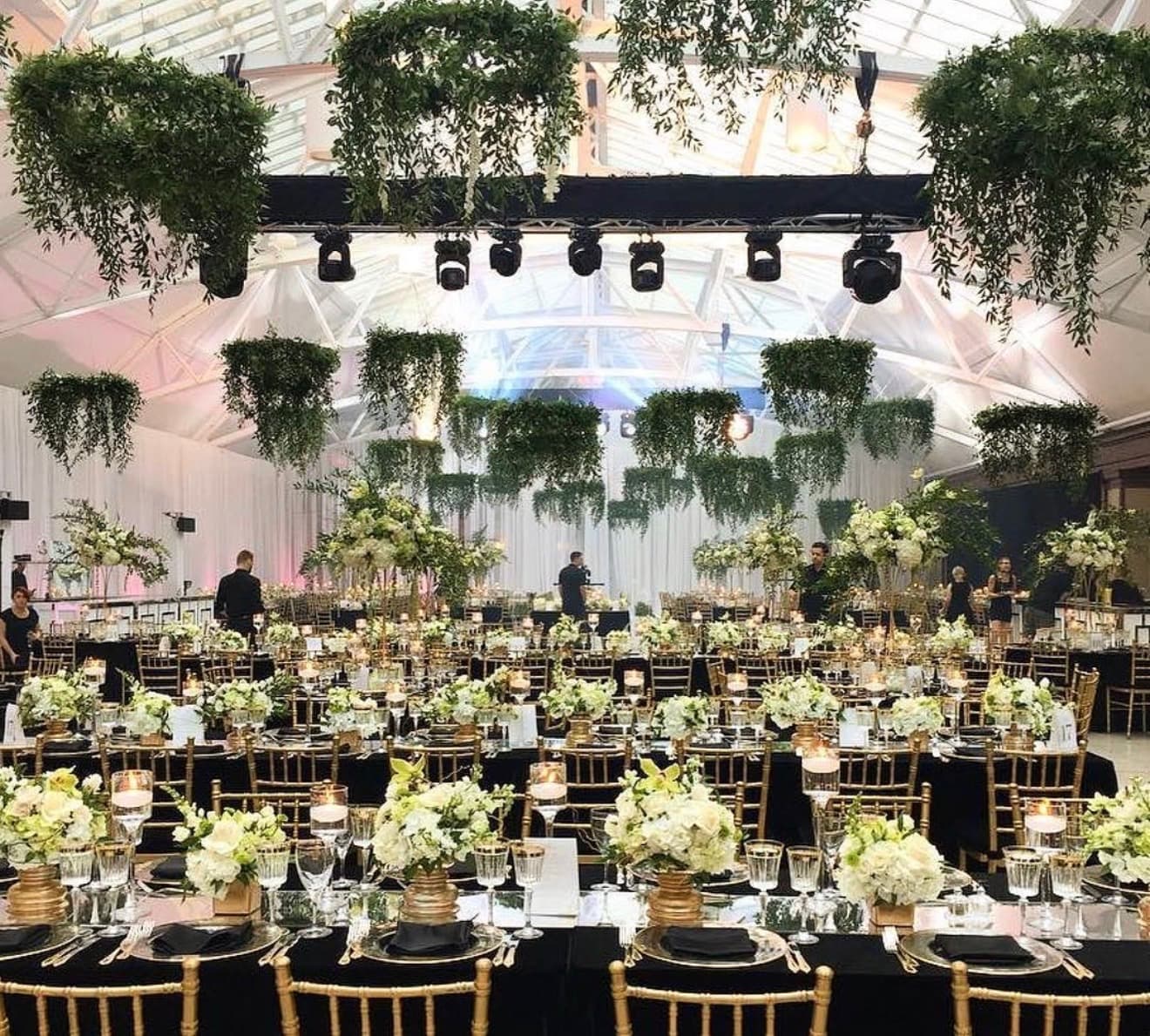 suspended greenery canopy installation over long banquet tables with white hydrangea and rose centerpieces at a Miami tented wedding reception