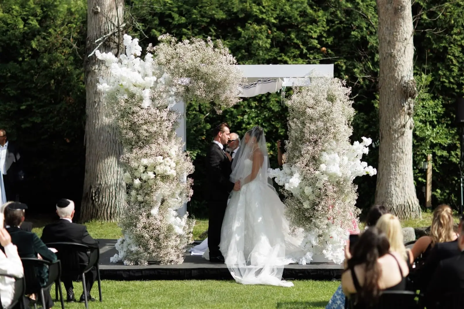 Lush white rose and baby's breath chuppah at an outdoor Jewish wedding ceremony in Miami
