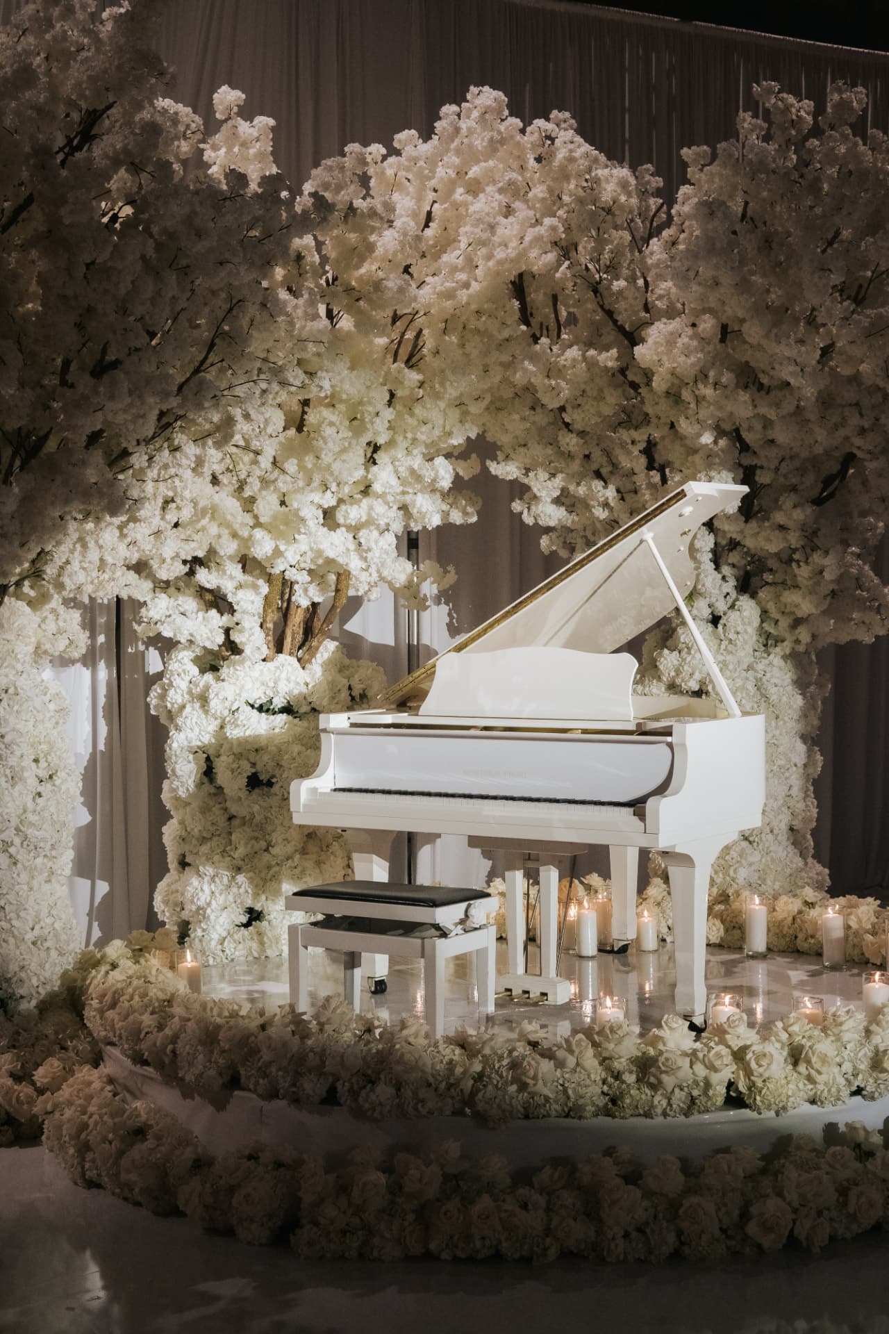 white blossom tree floral installation surrounding a white grand piano with candlelight at a luxury Miami wedding reception