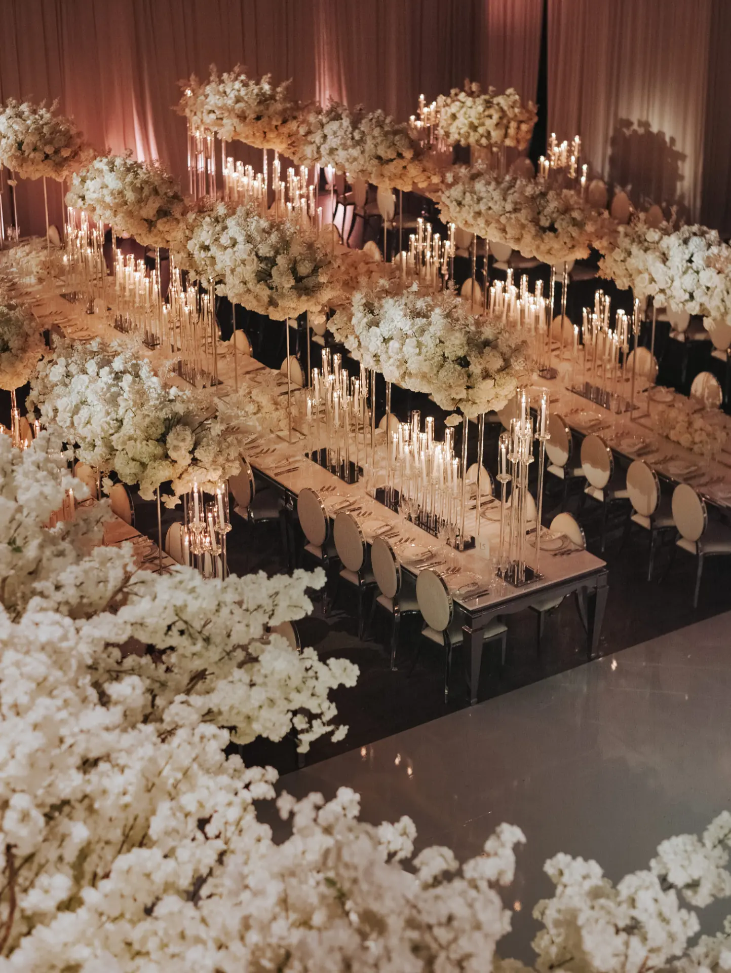 Miami wedding reception florals — mirrored banquet tables with elevated white blossom clouds and taper candles by Aura Design Flowers