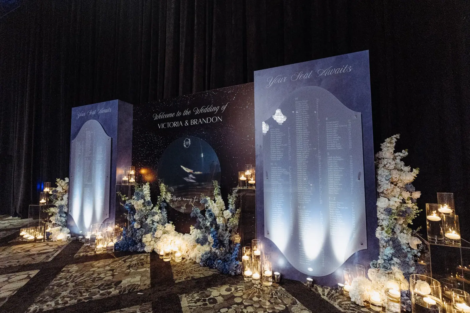 Celestial starry seating chart display with dusty blue and ivory florals, acrylic panels, and candlelight at a luxury Miami wedding reception