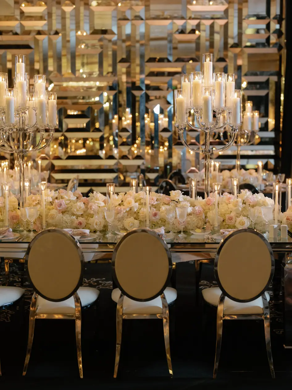 Crystal candelabras and gold mercury vessels paired with blush and ivory roses on a long table