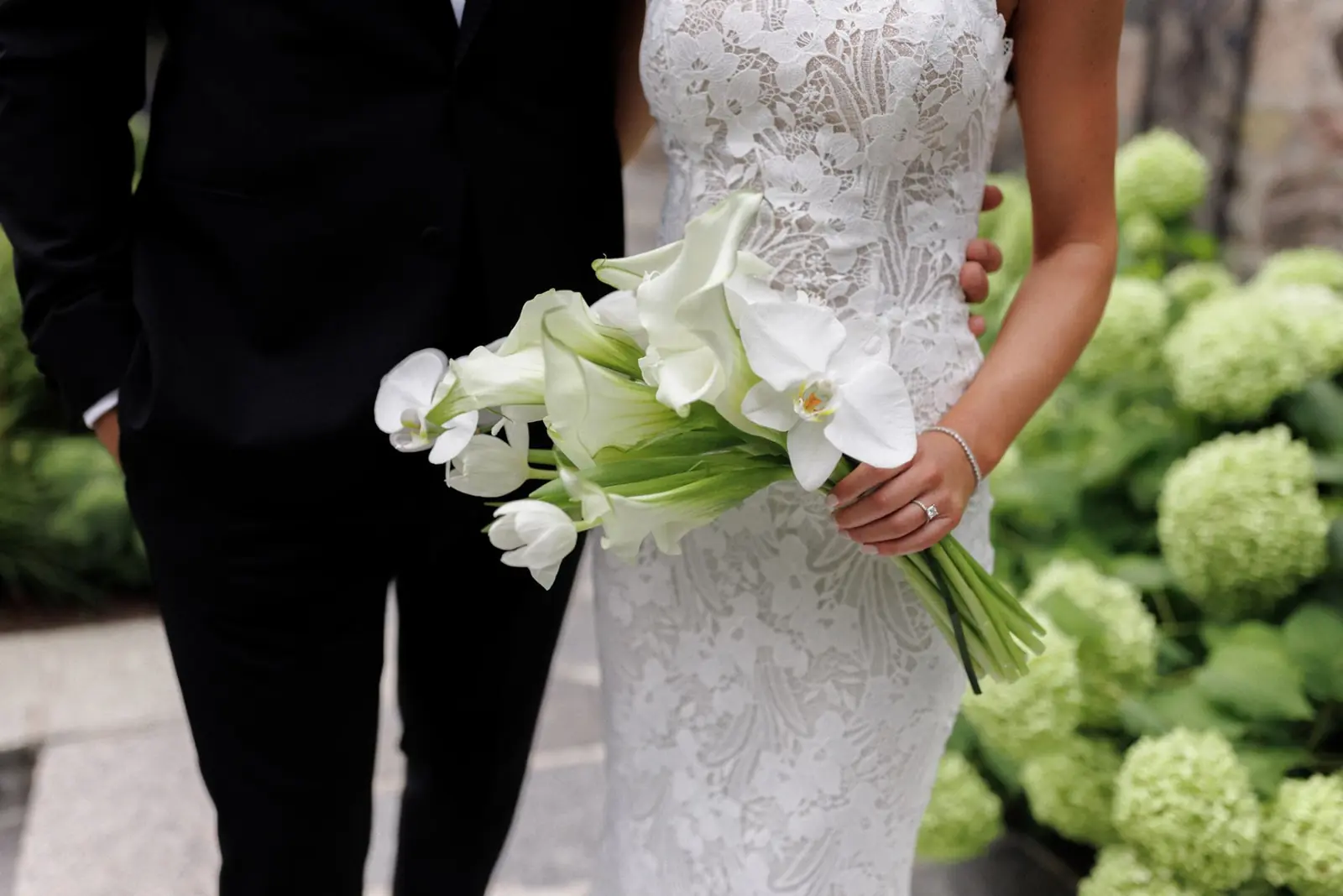 bride in lace gown holding all-white calla lily, phalaenopsis orchid and tulip bridal bouquet at luxury miami wedding