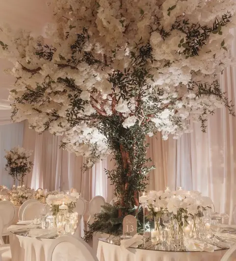 Eight foot white cherry blossom tree centerpiece with greenery over a mirrored ballroom table at a luxury wedding