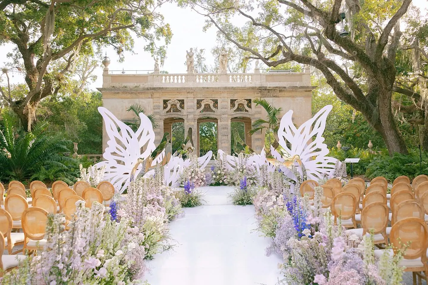 Luxury Miami wedding ceremony at Vizcaya with butterfly sculptures and lavender delphinium aisle florals