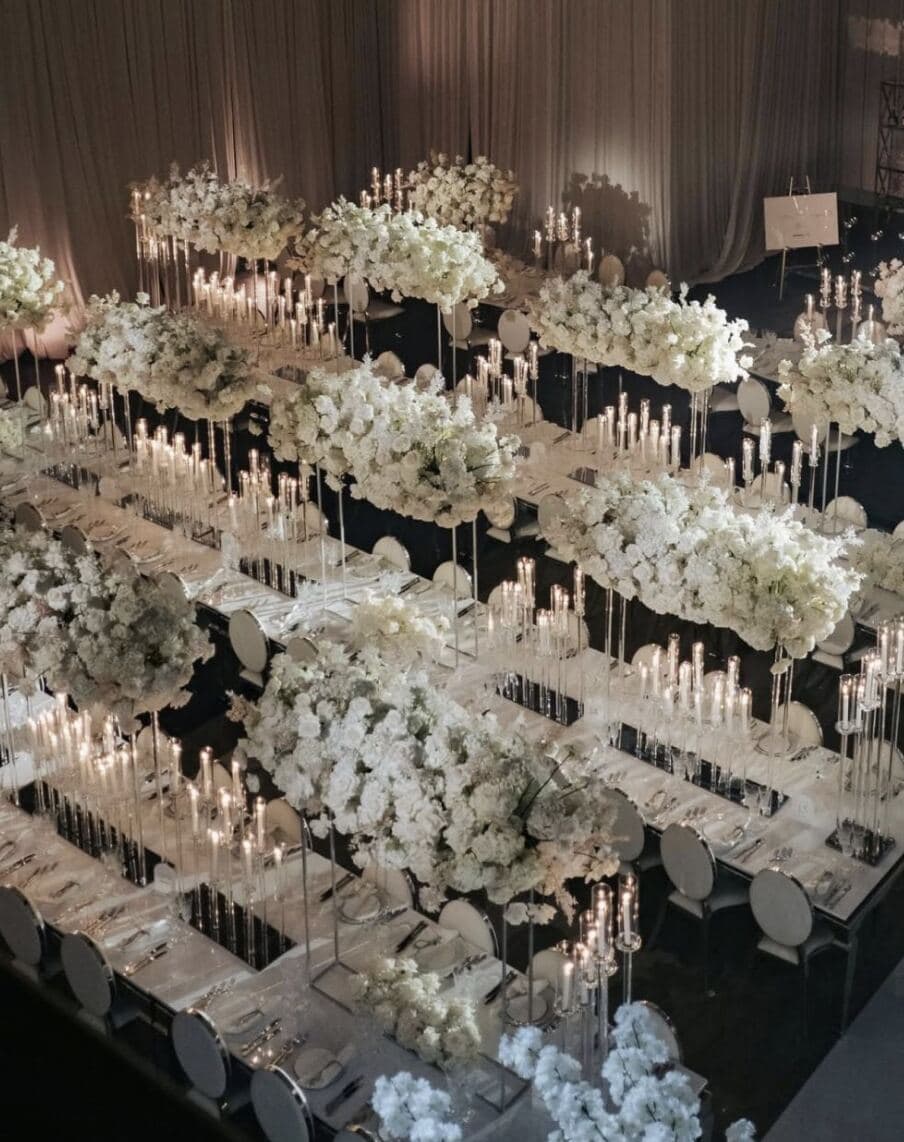 All-White Elevated Tablescape - Suspended white floral clouds and crystal taper candelabras over mirrored long tables by Aura Design Flowers Miami