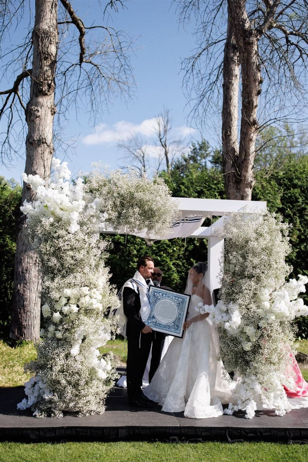Baby's Breath Chuppah - Cloud-like baby's breath and white rose chuppah under open sky by Aura Design Flowers Miami