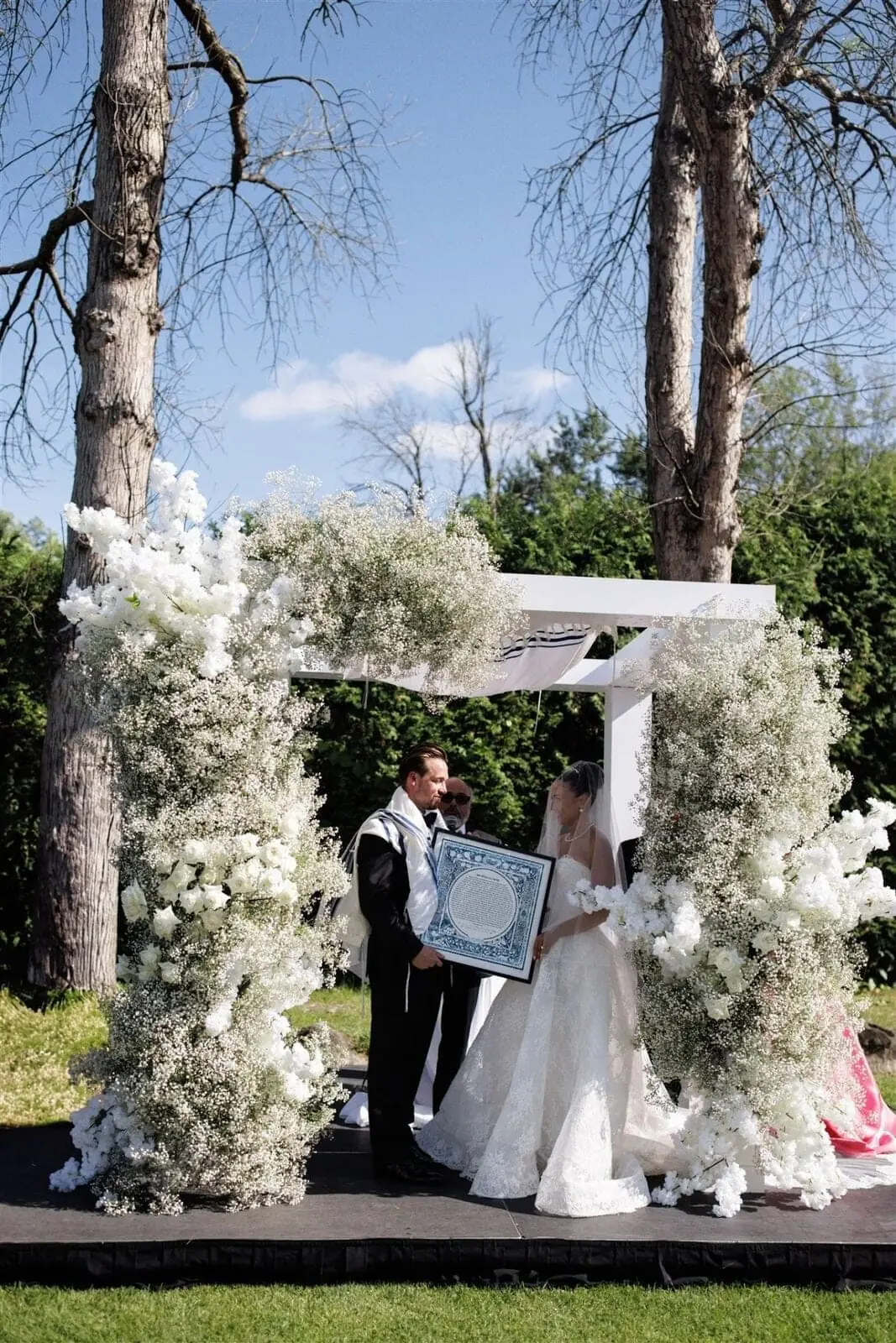 Baby's Breath Chuppah - Cloud-like baby's breath and white rose chuppah under open sky by Aura Design Flowers Miami