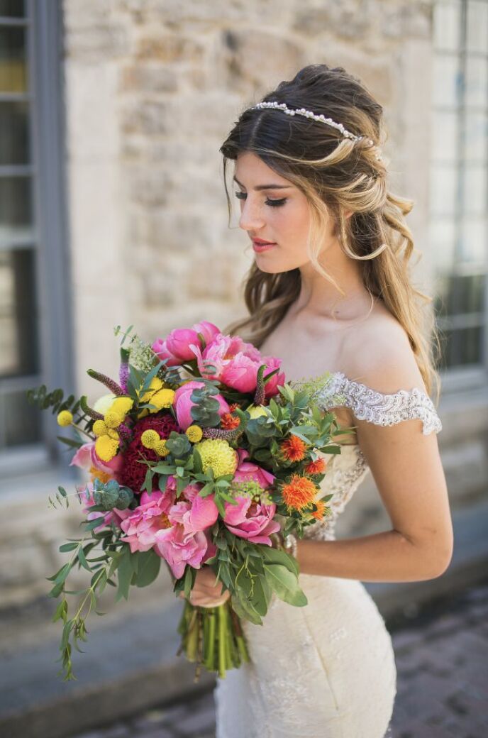 Bride with pearl headband holding a vibrant pink peony, billy ball, and wildflower bridal bouquet at a Miami wedding