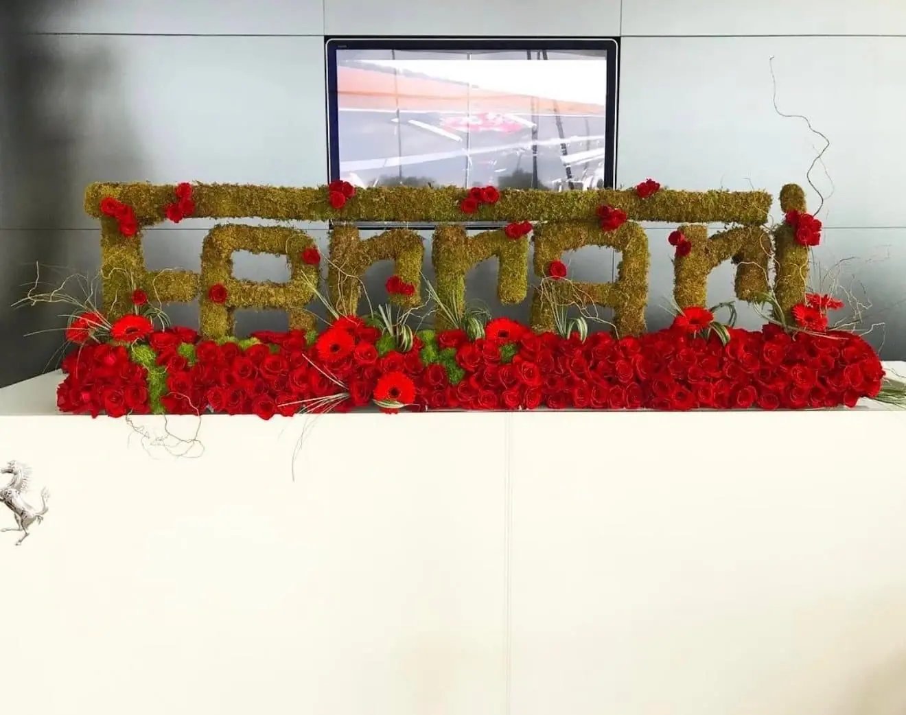 Ferrari corporate event florals in Miami: custom Ferrari logo floral sculpture in moss, red roses and gerbera daisies by Aura Design Flowers