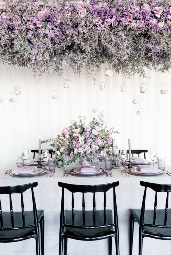 Suspended lavender rose and statice floral canopy with hanging glass baubles above editorial tablescape - lavender photoshoot