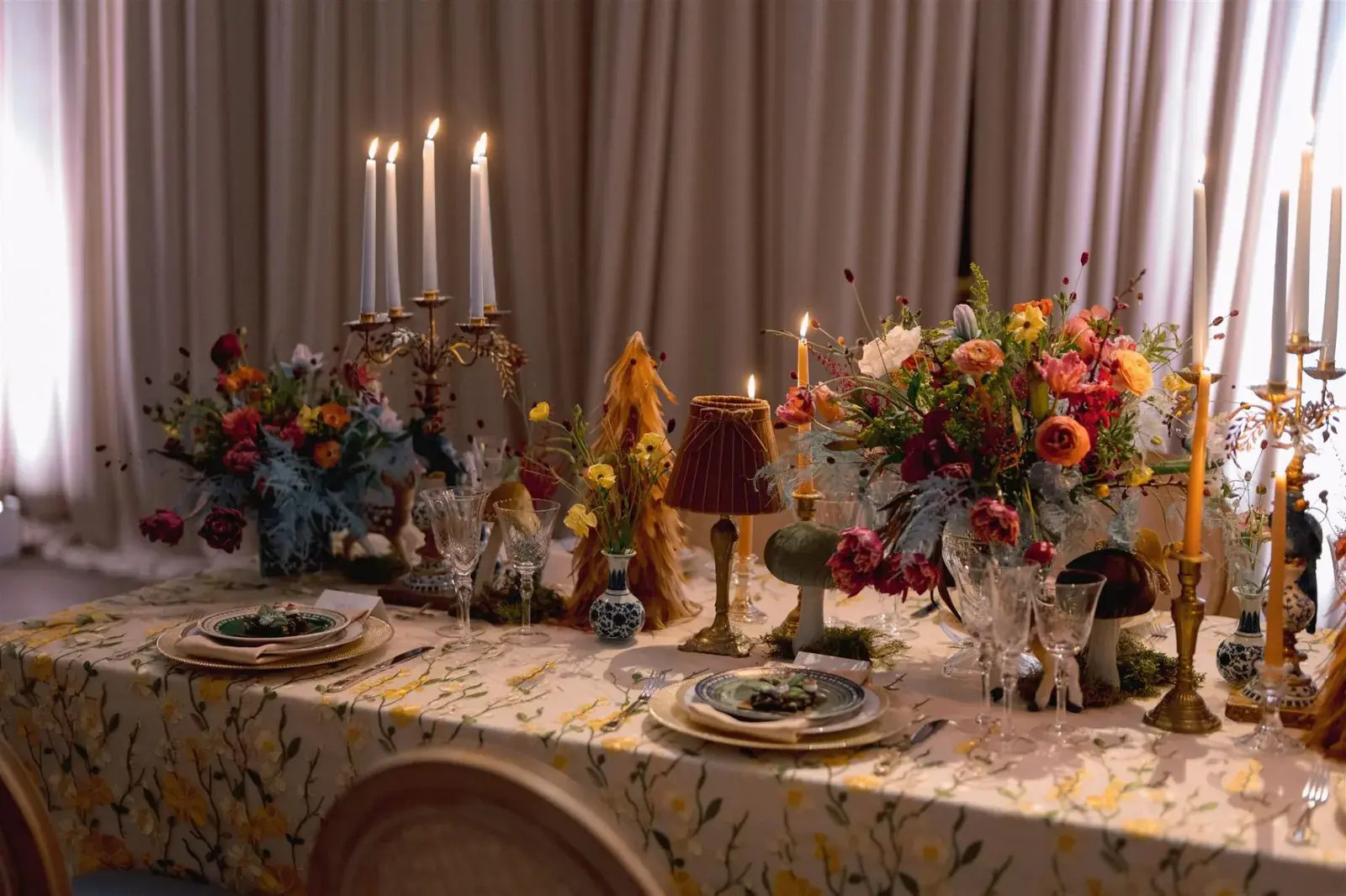 Intimate dinner setting with vintage candelabras, blue and white porcelain, and wild garden florals