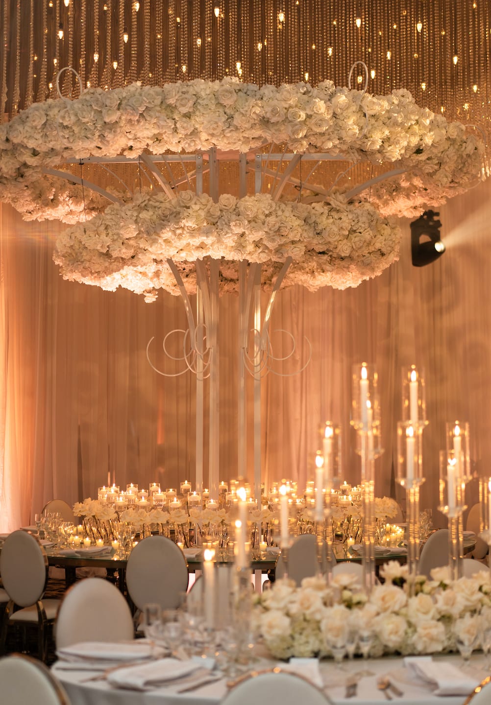 Luxury suspended white floral chandelier installation over Miami wedding reception tablescape