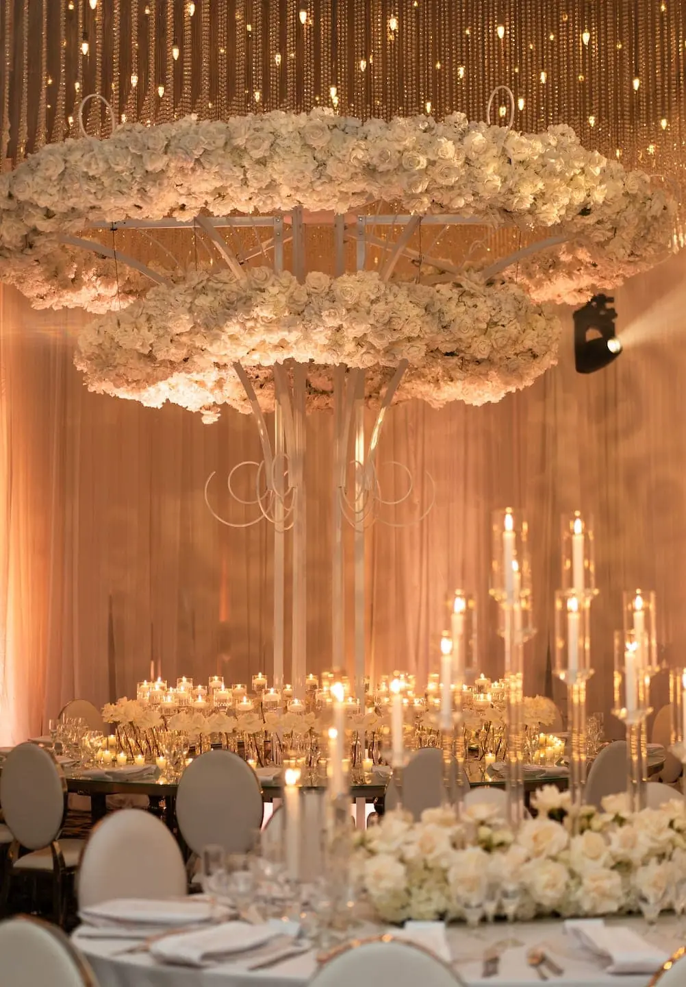 Luxury suspended white floral chandelier installation over Miami wedding reception tablescape