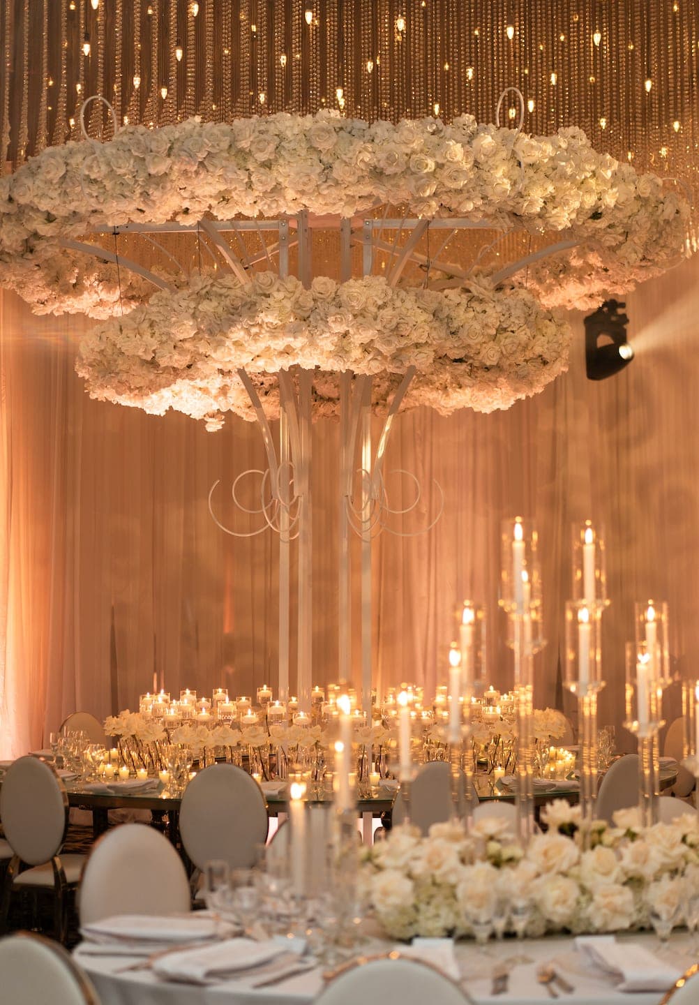 Luxury suspended white floral chandelier installation over Miami wedding reception tablescape