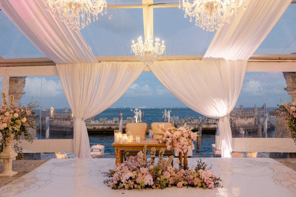 Sweetheart Table - Oceanfront reception with cascading florals & chandeliers by Aura Design Flowers Miami