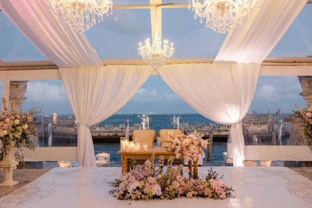 Sweetheart Table - Oceanfront reception with cascading florals & chandeliers by Aura Design Flowers Miami