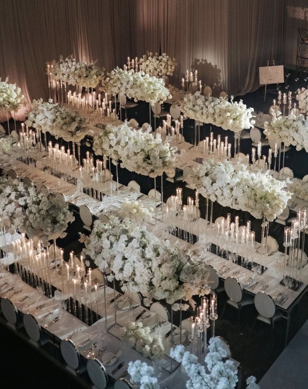 Grand ballroom wedding reception with towering white floral centerpieces