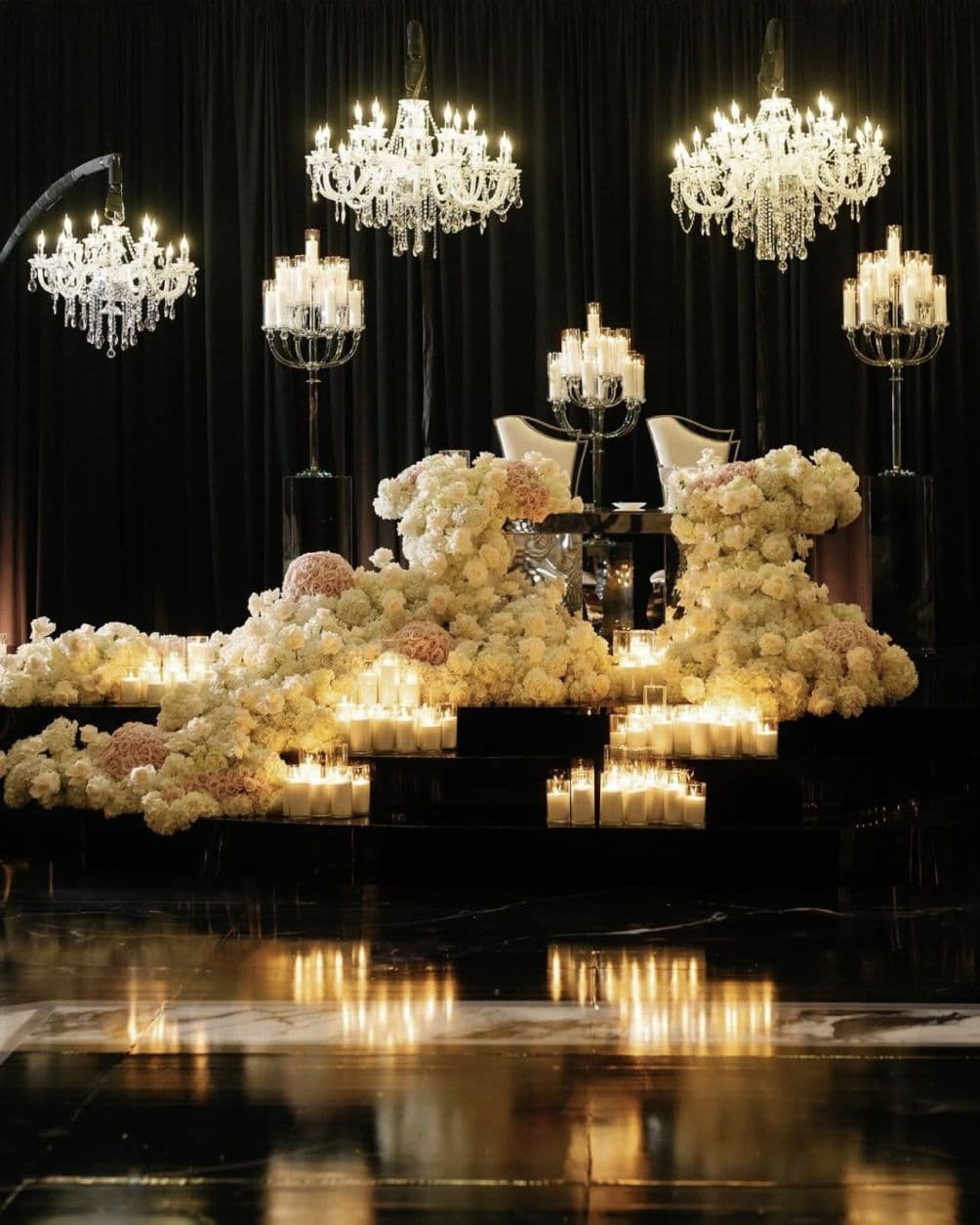 Dramatic sweetheart table with cascading flowers and crystal chandeliers