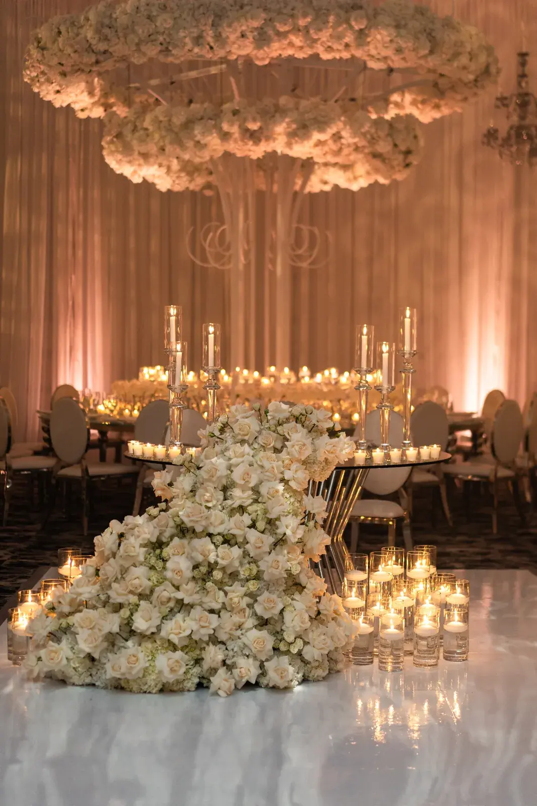 Cascading white rose and hydrangea sweetheart table with floral chandelier and candlelit ballroom in Miami